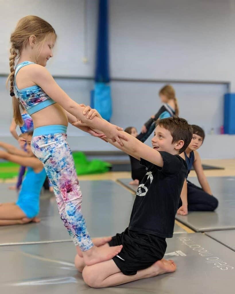 a boy and a girl performing a counter balance and calypso gymnastics clubs summer camp